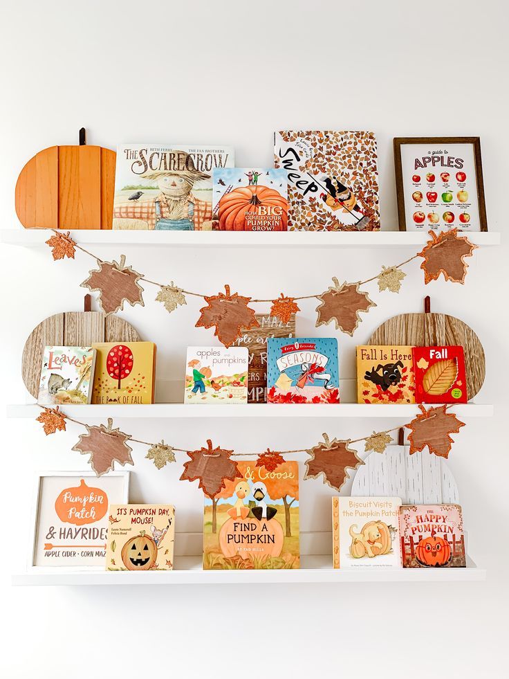 the books are lined up on the shelves with autumn decorations and pumpkins hanging from them