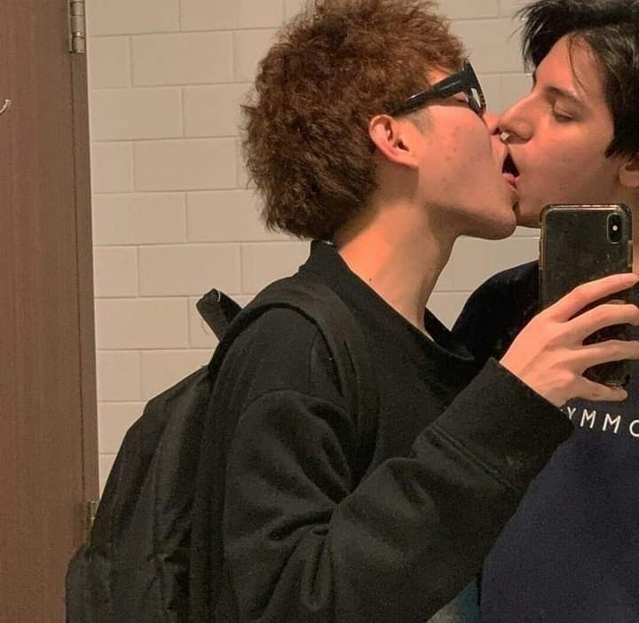 two people kissing each other in front of a mirror