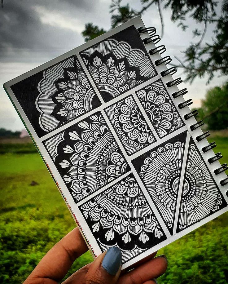 a hand holding up a notebook with an intricate design on it