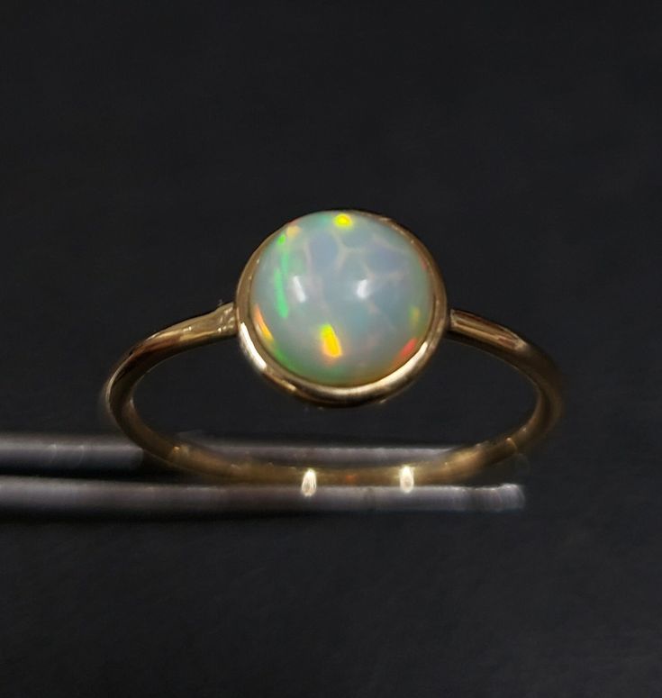 1. ethiopian opal 14k gold ring 2. made to order  3. gemstone - ethiopian opal 4. jewelry type - gold ring 5. total weight - 1.300 gram approx 6. opal weight - 1.03 cartas 7. gold weight - 1.093 gram approx 8. opal size - 7 mm 9. gold purity - 14k 10. handmade items 11. band size - 1.50 mm 12. high polished 13. aaa quality ring  14. stackable ring 15. 1 quantity available 16. ready to dispatch in 1 -2 days. 17. rare size / rare fire Gold Ethiopian Opal Ring Hallmarked, Yellow Gold Ring With Ethiopian Opal And Birthstone, Yellow Gold Ethiopian Opal Ring With Birthstone, Yellow Gold Ethiopian Opal Birthstone Ring, Gold Ethiopian Opal Birthstone Ring, Yellow Gold Moonstone Ring With Ethiopian Opal For Gift, Yellow Gold Moonstone Ring With Ethiopian Opal, Ethiopian Opal Moonstone Ring In Yellow Gold For Gift, Gold Ethiopian Opal Cabochon Ring