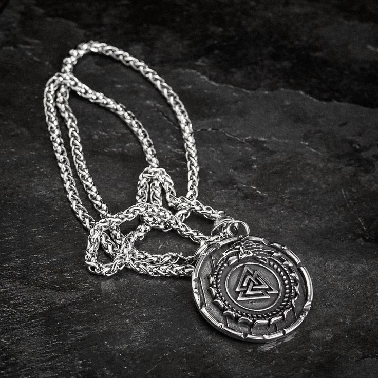 This stainless steel necklace is perfect for those who want to add a little bit of mythology to their wardrobe. The shield style pendant features the mythical serpent Jormungand, encircling a Valknut symbol. Whether you're dressing up for a day at the office or dressing down for a night out on the town, this necklace is sure to make a statement. Also features a Helm of Awe on the reverse with the inscription: "The brave shall live forever in the halls of Valhalla" Pendant is approx. 1.5" across Symbolic Silver Tarnish Resistant Medallion Necklace, Symbolic Silver Medallion Necklace, Symbolic Silver Medallion Necklace Tarnish Resistant, Symbolic Silver Tarnish-resistant Medallion Necklace, Viking Style Engraved Metal Necklaces, Viking Style Silver Stainless Steel Jewelry, Viking Style Silver Round Pendant Necklace, Viking Style Silver Stainless Steel Necklaces, Silver Viking Stainless Steel Necklaces