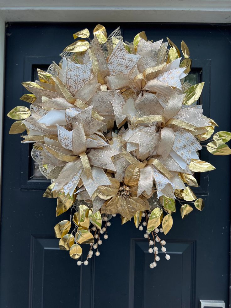 a wreath on the front door with gold leaves and pearls hanging from it's side