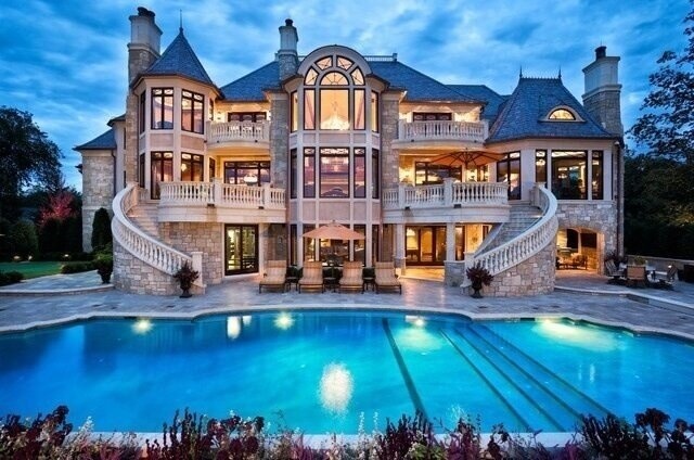 a large mansion with a swimming pool in the front yard and stairs leading up to it