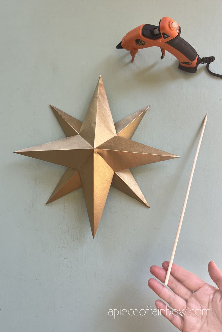 a hand holding a stick next to a metal star