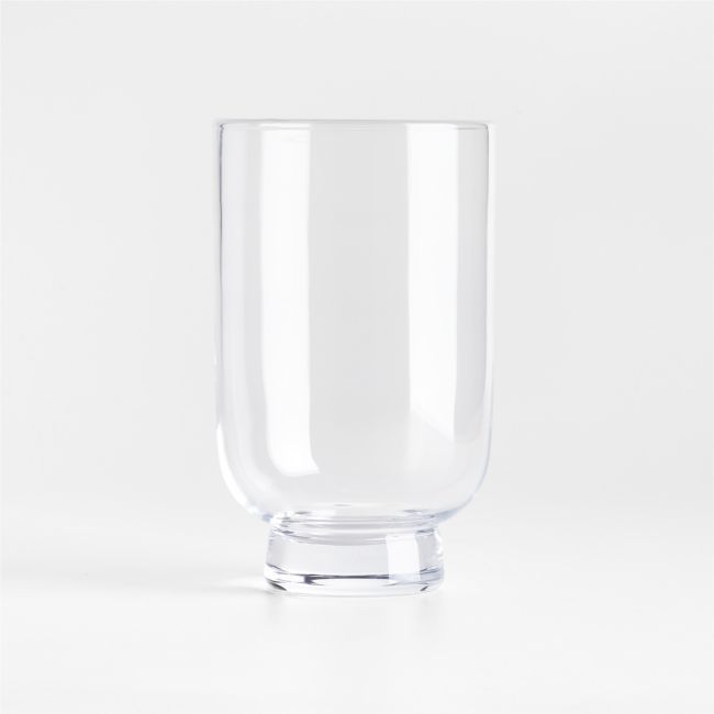 a clear glass is sitting on a white surface with no one around it and the bottom half empty