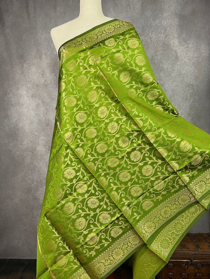 Mehndi Green Banarasi Soft Silk Dupatta with Zari Weaved with flower designs all over the dupatta. Note - Dupatta has black tassels on the ends. Item: DupattaBase color : Mehndi Green (Heena Green Color)Fabric : Banarasi Silk (Non-Pure Silk)Work : Zari Weaved with tasselsWidth of the dupatta - 35 inches (approx)length of the dupatta - 88 inches (approx) Store Policies- No return or exchange will be accepted for color variations.- No return or exchange will be accepted if the color does not match your other clothing or your partners or anyone else.- Since this Dupatta is handmade hence little inconsistencies may be there however it is not considered as a defect.- Zari or thread coming out at the ends or anywhere on the dupatta or on folds is not considered as defects.- Slight variation in a Elegant Green Choli For Puja, Green Tilla Dupatta For Puja, Green Art Silk Traditional Wear With Tilla, Green Art Silk Traditional Wear With Tilla Detail, Green Self-design Dupatta For Puja, Traditional Tilla Dupatta For Festive Occasions, Traditional Chanderi Wear With Tilla For Puja, Green Banarasi Silk Dupatta Chandbali, Green Bollywood Saree With Tilla