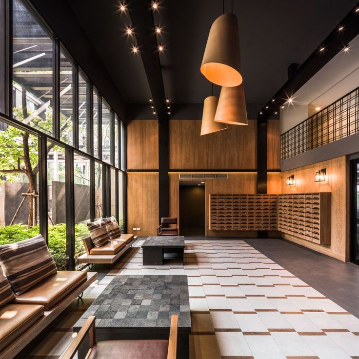 an empty lobby with benches and lights hanging from the ceiling