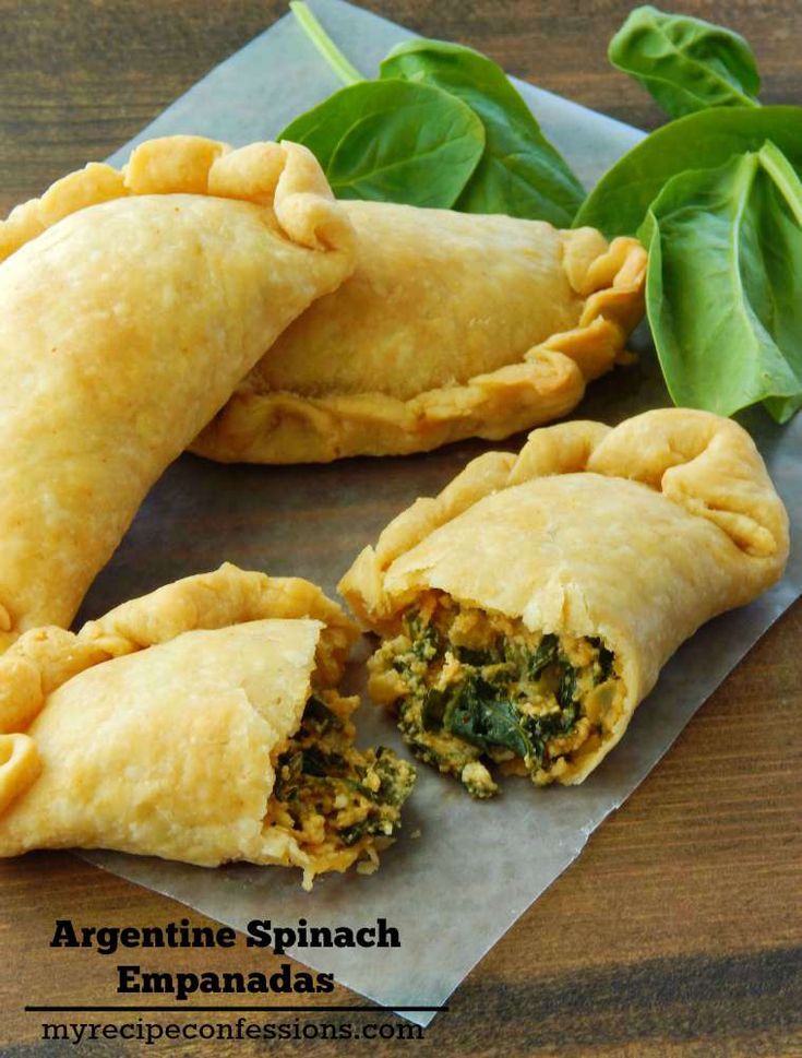 two pieces of spinach empanadas on a piece of wax paper with leaves