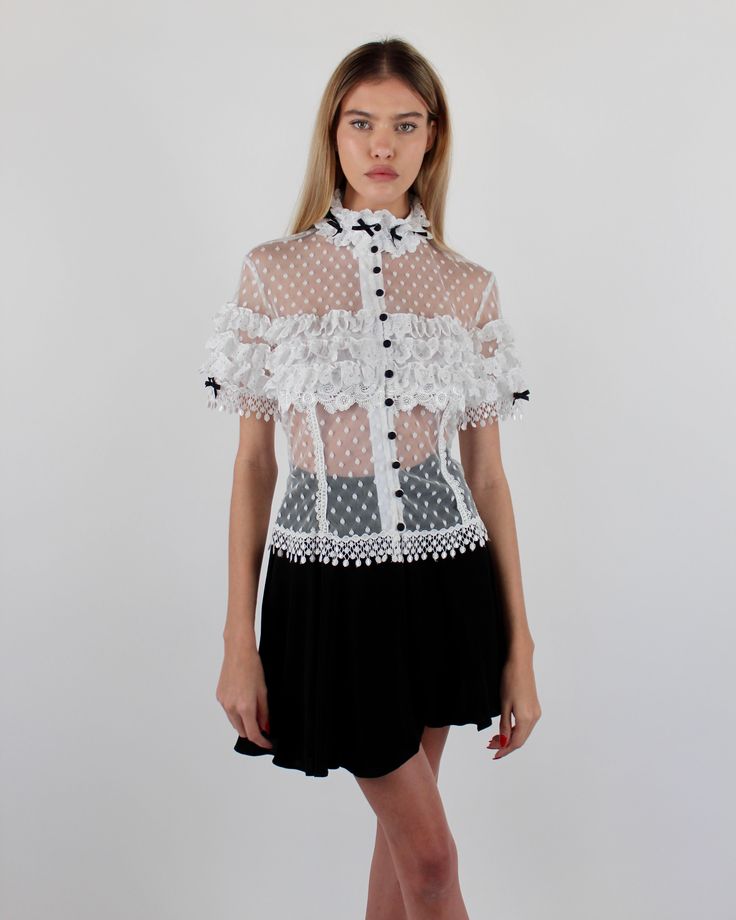 Introducing the elegant Alicia Blouse, crafted from Swiss Point D’Esprit with cotton lace ruffles, Venise trims, and satin baby bows. This soft, fitted blouse features an empire focus, adorned with delicate ruffles at the neckline and sleeves, complemented by satin pearl buttons at the center front. Available in White and Black or Black on Black. Swiss Point D’Esprit Cotton lace ruffles with Venise trims Satin pearl buttons Dry clean only Each piece is made to order and handcrafted in our atelie Tap Shorts, Fitted Blouse, Fitted Blouses, Black On Black, Spring Summer 2024, Lace Ruffle, Pearl Buttons, Baby Bows, Cotton Lace