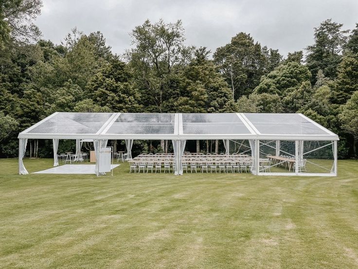 a large white tent set up in the middle of a field with tables and chairs