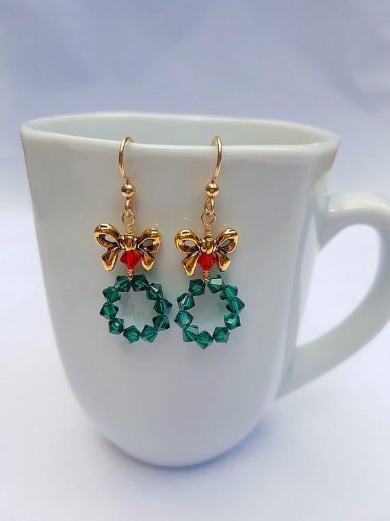 These adorable Christmas Wreath Earrings are Handmade with Emerald Green and Red Swarovski Crystal Bicone Beads and Tierra Cast, Lead-Free Pewter Bow Beads. 14K Gold Filled Ear Wire by Tierra Cast has been used. Meticulously wire wrapped with Tarnish Resistant 14k Gold Plated Wire.  Charming yet Handmade Gold Christmas Earrings, Christmas Jewelry Gift With Matching Earrings, Christmas Jewelry Gift Set With Matching Earrings, Christmas Jewelry Set As Gift With Matching Earrings, Handmade Gold Earrings For Christmas, Handmade Jewelry For Holiday Celebration, Handmade Holiday Jewelry For Celebration, Festive Christmas Jewelry With Matching Earrings, Christmas Celebration Jewelry With Matching Earrings