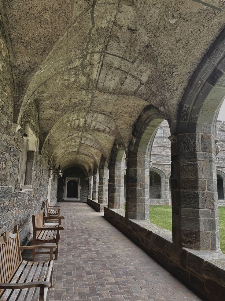 an old stone building with benches lined up against the wall