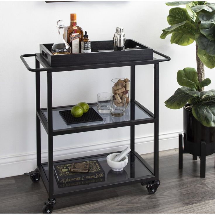 a bar cart with drinks on it in front of a potted plant