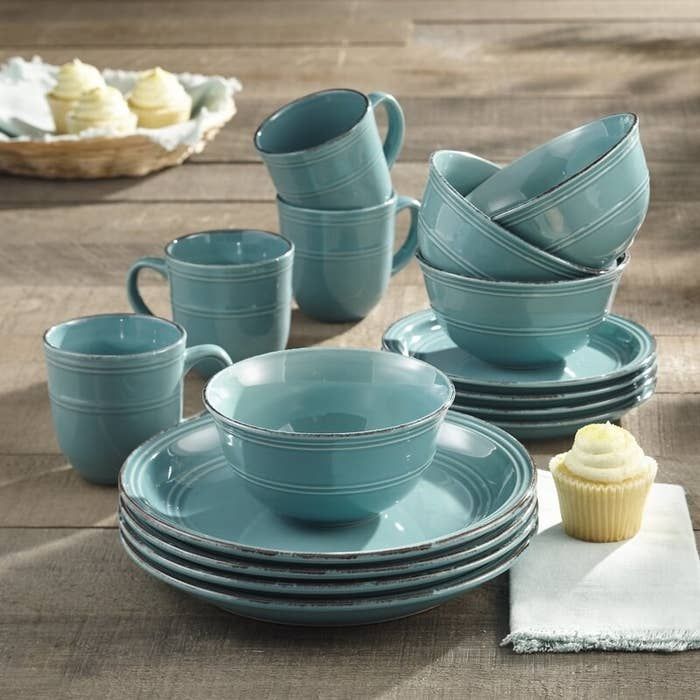 a table topped with blue dishes and cupcakes