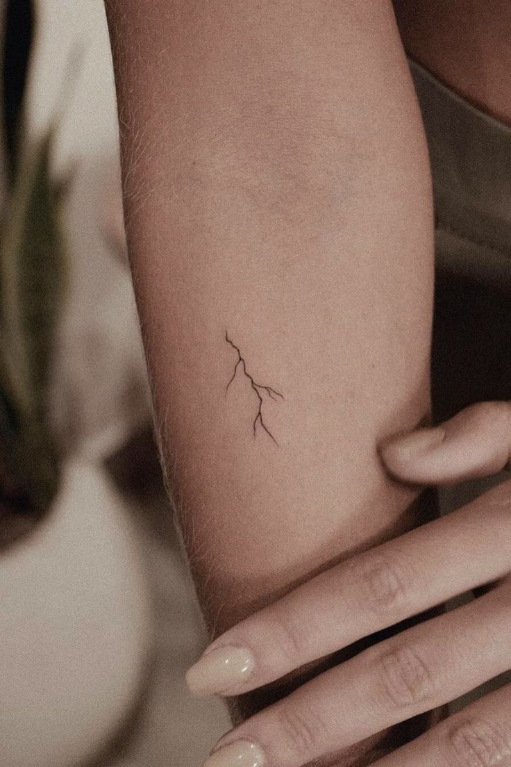 a woman's arm with a small branch tattoo on the left side of her arm