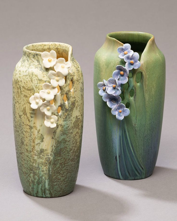 two vases with flowers on them sitting next to each other