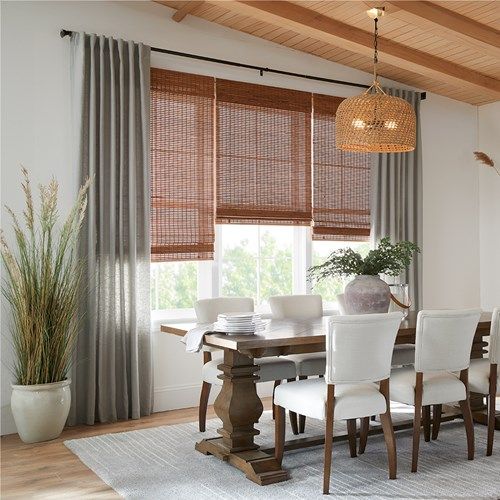 a dining room table with white chairs next to a window