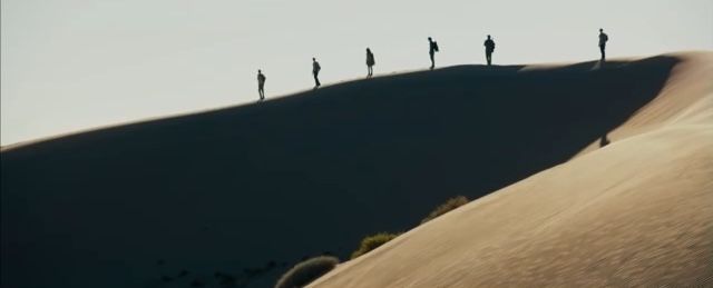 several people standing on top of a sand dune