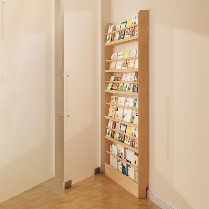 a bookshelf in the corner of a room with hard wood floors and white walls