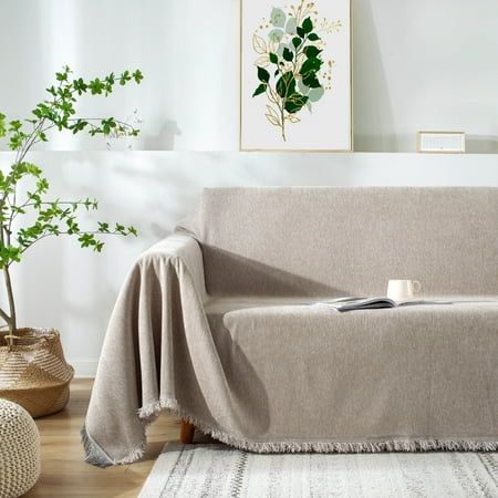 a living room with a couch covered in a blanket and potted plants on the floor