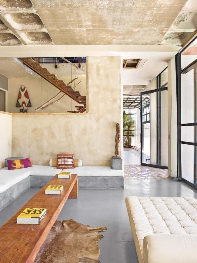 a living room filled with lots of furniture and a stair case in the middle of it