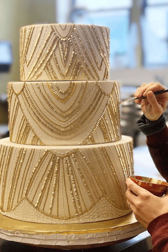 a woman is decorating a three tiered cake