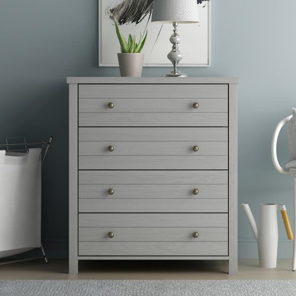 a white dresser sitting next to a lamp on top of a table