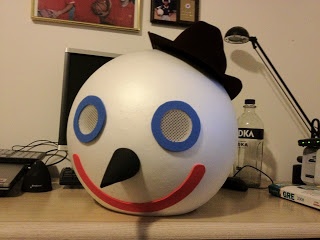 a large white ball with a face painted on it sitting on a desk next to a lamp