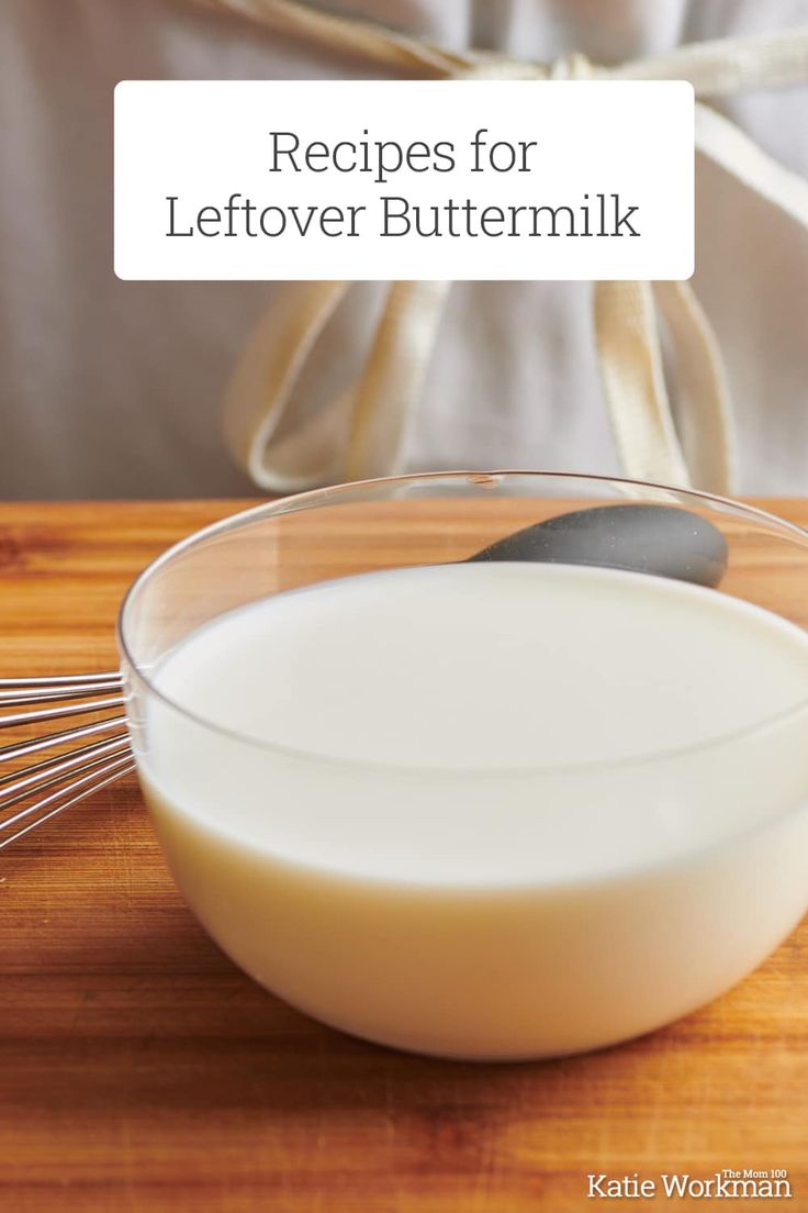 a glass bowl filled with milk and whisk on top of a wooden table