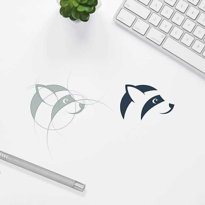 a raccoon logo next to a keyboard and mouse on a white desk top