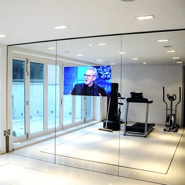 a room with mirrors, treadmills and a television on the wall in front of it