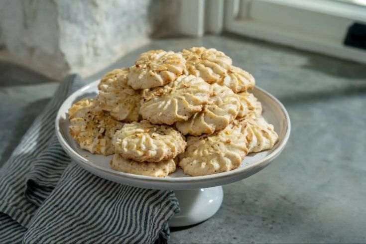 a plate full of cookies sitting on top of a table next to a towel and window