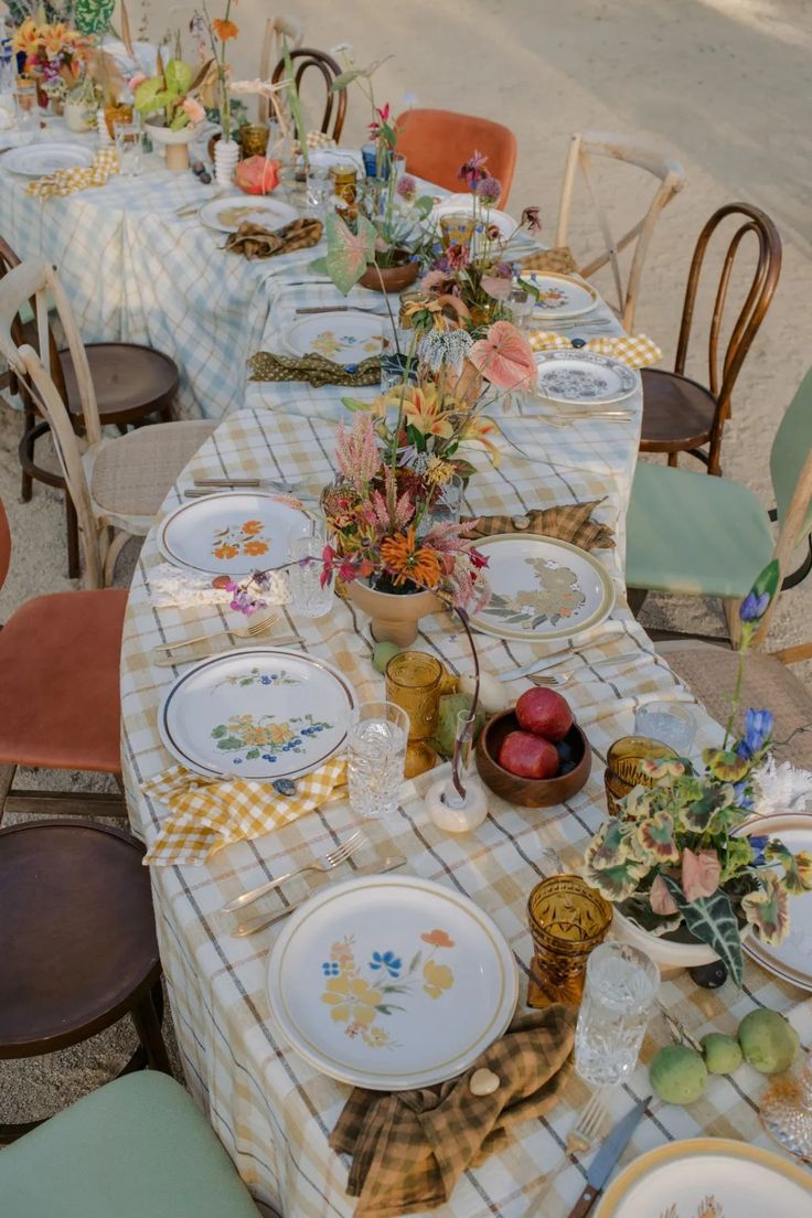 a table set up with plates and flowers on it for an outdoor dinner or party