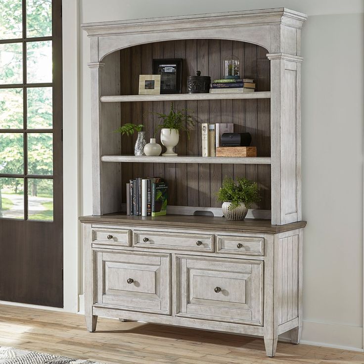 a white bookcase with drawers and books on it