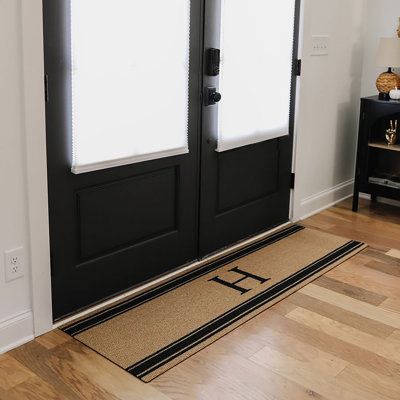 a black door with two sidelights and a rug on the floor next to it