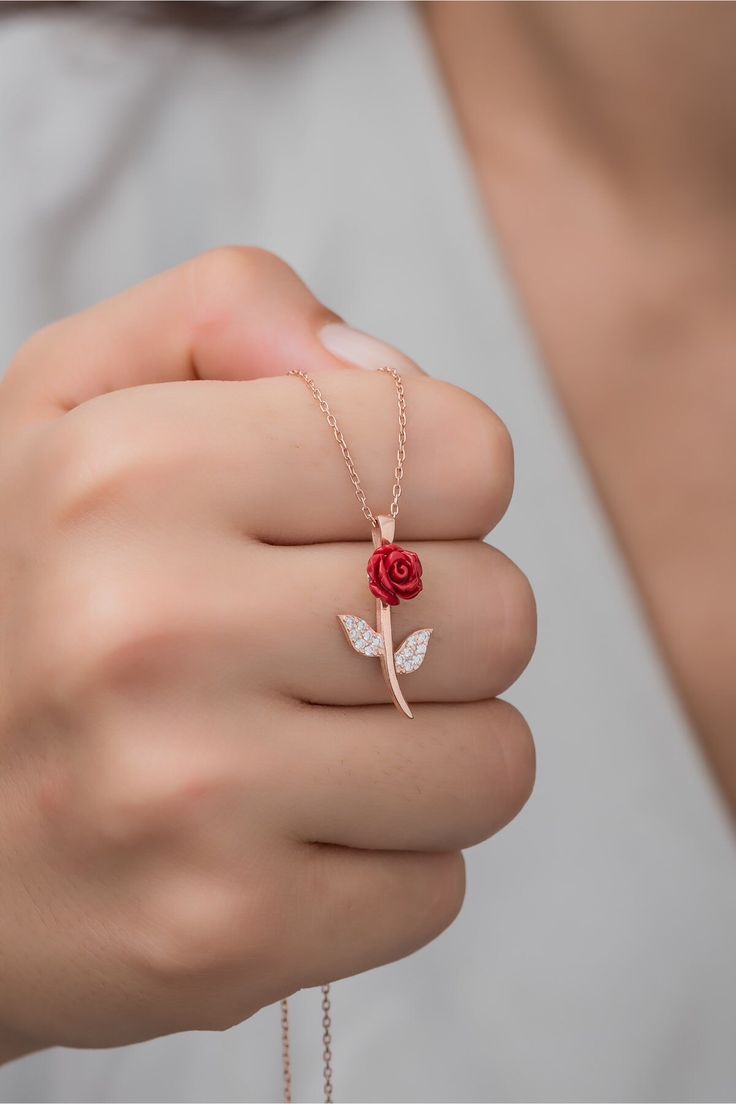 a woman wearing a rose ring with two leaves on it's side and a chain around her wrist