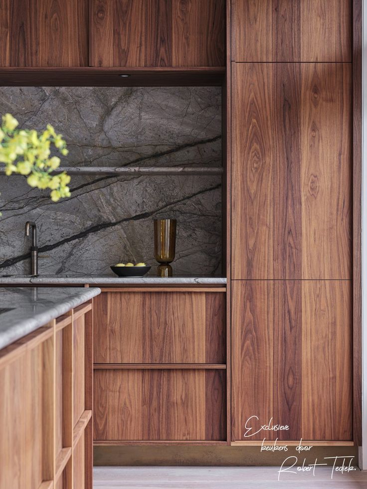 a kitchen with wooden cabinets and marble counter tops, along with a vase filled with flowers