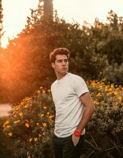 a young man standing in front of some bushes