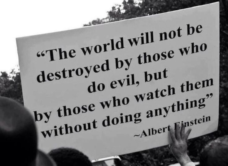 a man holding a sign that says the world will not be destroyed by those who do evil, but by those who watch them without doing anything