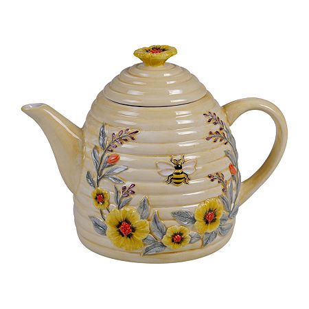 a ceramic teapot with yellow flowers and a bee on it