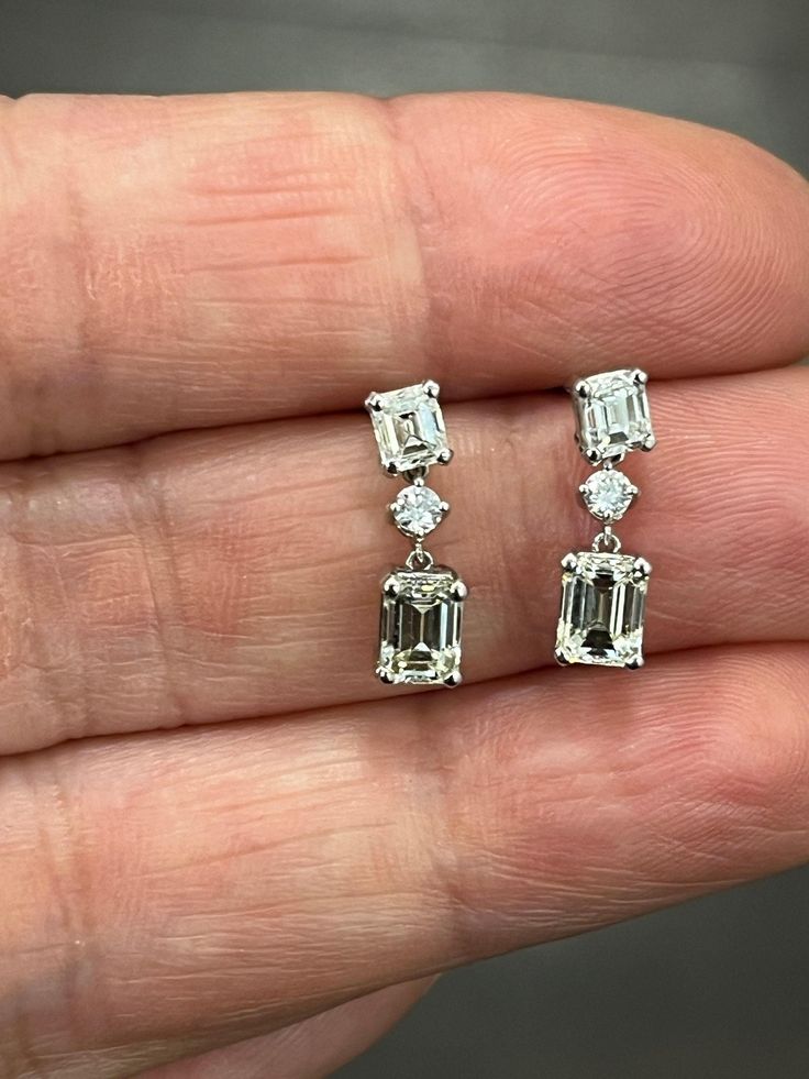 These stunning 1.72 ct emerald cut diamond dangle earrings feature 6 diamonds total with 2 round diamonds set in platinum. The diamonds are I to K in color, and VS1/VS2 in clarity. A great addition to any wardrobe. Elegant Platinum Emerald Cut Diamond Earrings, Elegant Emerald Cut Platinum Diamond Earrings, Luxury Emerald Cut Diamond White Diamond Earrings, Diamond Brilliant Cut Octagon Earrings, Timeless Emerald Cut Diamond Earrings, Emerald Cut Diamond Earrings In White Gold, Diamond Earrings With Brilliant Cut In Octagon Shape, Diamond Octagon Earrings With Brilliant Cut, Baguette Diamond Earrings With Emerald Cut