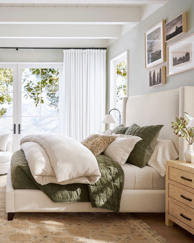 a bed with white sheets and pillows in a bedroom next to a large glass window