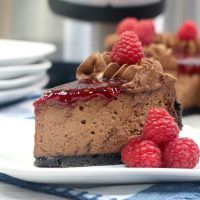 a piece of chocolate cheesecake on a plate with raspberries