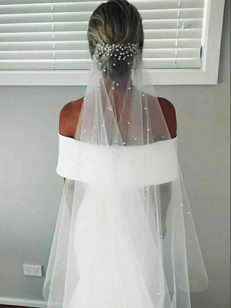 the back of a bride's wedding dress, with her veil draped over her shoulder