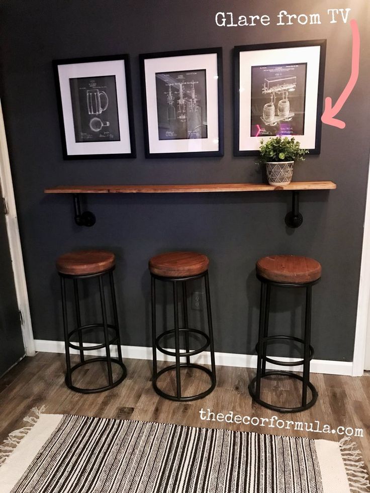 three stools are in front of a bar with pictures on the wall above it