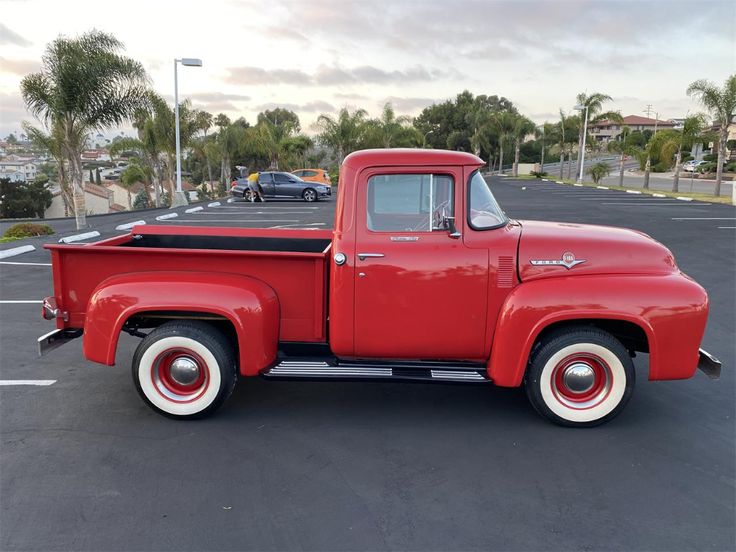 an old red truck parked in a parking lot