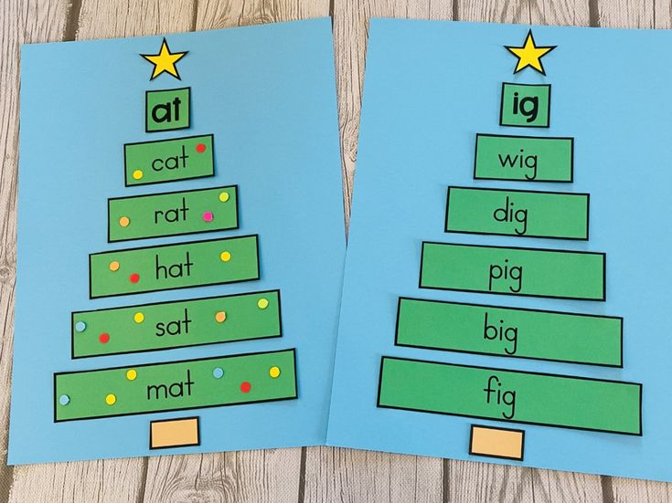 two christmas tree cut outs on top of blue paper with yellow and green stars in the middle