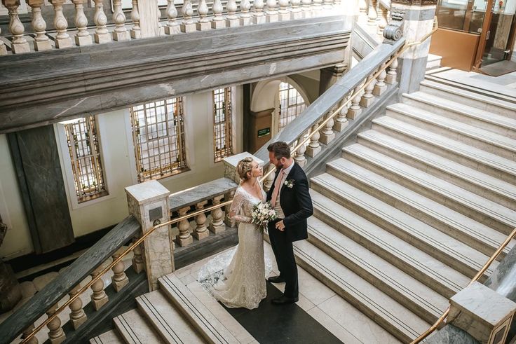 a bride and groom are standing on the stairs