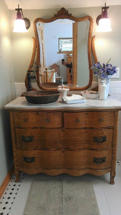 a bathroom with a sink, mirror and dresser in it's centerpieces