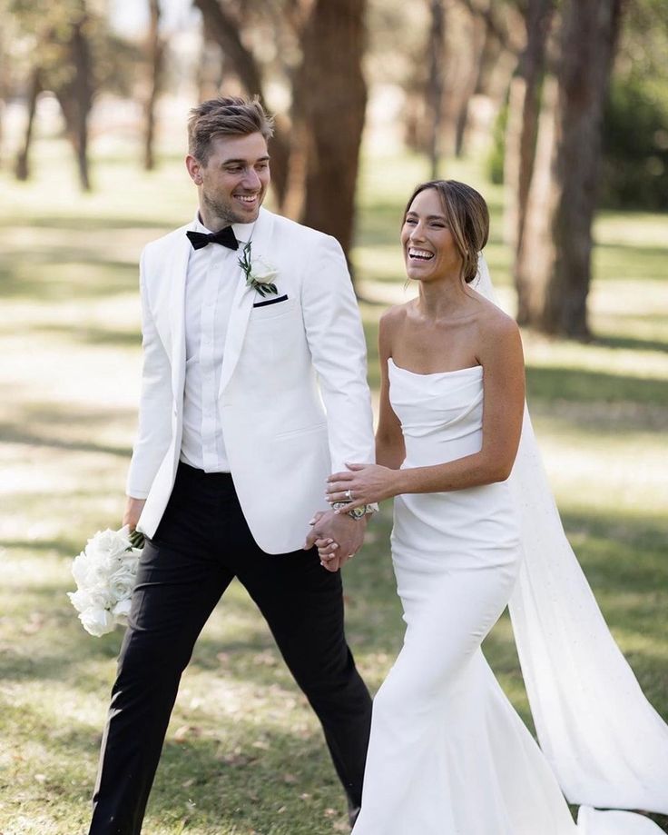 a newly married couple walking through the grass